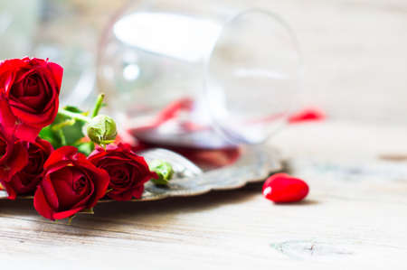 Table setting for St. Valentines day with glasses of red wine, present box and red roses  in rustic styleの写真素材