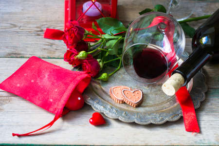 Table setting for St. Valentines day with glasses of red wine, present box and red roses  in rustic styleの写真素材