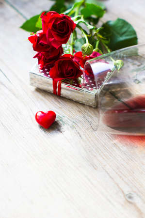 Glasses of red wine, present box and red roses for Valentines day celebrationの写真素材