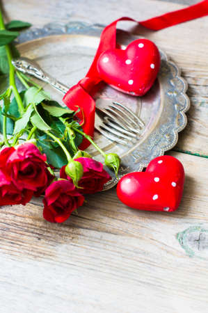 Table setting for St. Valentines day with glasses of red wine, present box and red roses  in rustic styleの写真素材