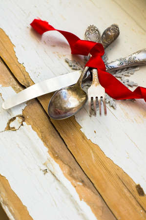 Vintage silverware with red ribbn on rustic backgroundの写真素材
