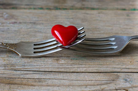 Red heart between two vintage forks on rustic wooden backgroundの写真素材
