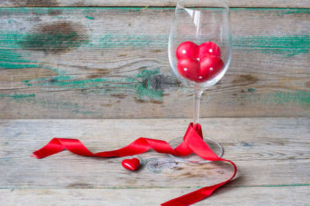 Wine glass with heart shaped gifts for Valentines day on the rustic backgroundの写真素材