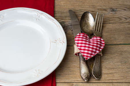 Valentines table setting with vintage silverware and red heart as a decorationの写真素材