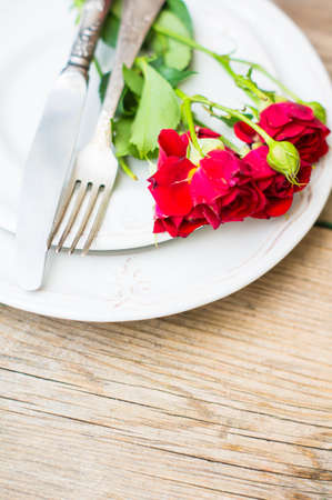 Table setting for St. Valentines day with glasses of wine, present box and red roses  in rustic styleの写真素材