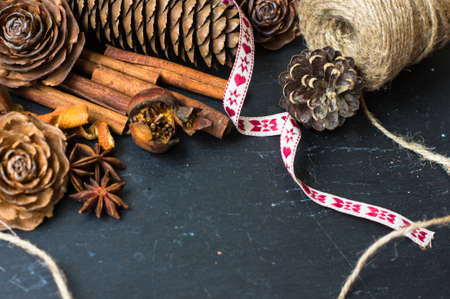 Christmas time spices and pine cones on rustic background