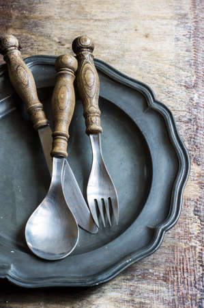 Vintage plate with old styled silverware on wooden rustic backgroundの写真素材