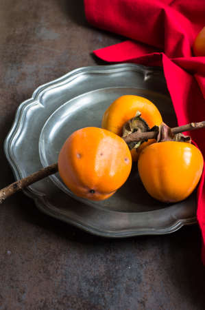 Ripe persimmons fruits on rustic backgroundの写真素材