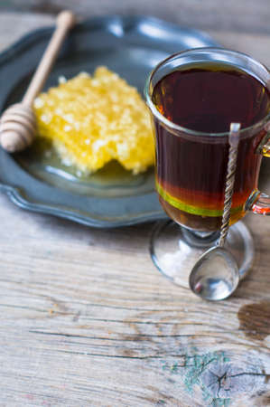 Glass of tea with lemon and honey on rustic kitchen