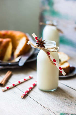 Christmas cake on vintage plate and rustic bottles with milk on rustic backgroundの写真素材