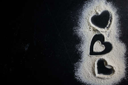 Hearts made with flour on the black backgroundの写真素材