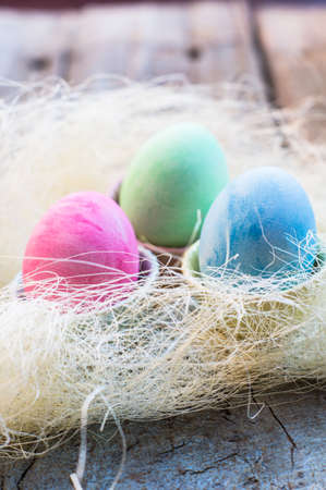 Easter eggs in a nest on rustic background