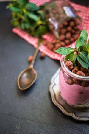 Chocolate breakast flakes with yogurt and mint in vintage glass on rustic backgroundの写真素材