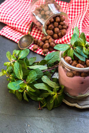 Chocolate breakast flakes with yogurt and mint in vintage glass on rustic background