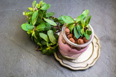 Chocolate breakast flakes with yogurt and mint in vintage glass on rustic background