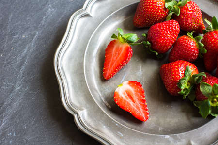 Fresh organic strawberries in vintage plate on  rustic backgroundの写真素材