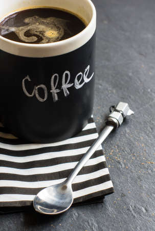 Cup of coffee with coffee word with chalk and stripped napkin on dark backgroundの写真素材