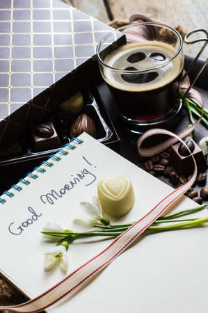 Present box and cup of coffee with candies on rustic tableの写真素材