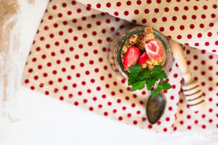 Healthy breakfast granola with strawberry, vintage silverware and glassの写真素材