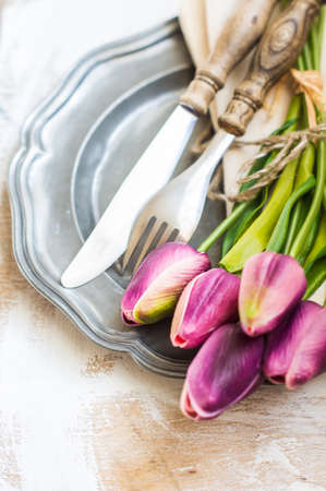 Spring time table setting with tulip flowers and vintage style silverware and tablewareの写真素材
