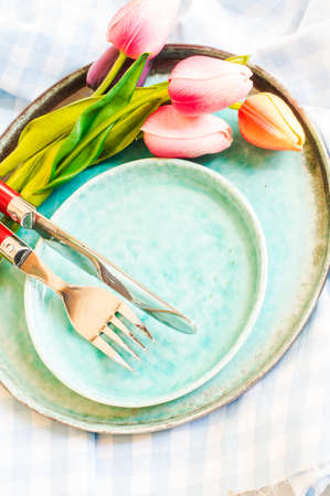 Spring time table decoration with tulip flowers and turquoise platesの写真素材