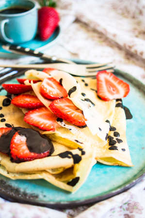 Breakfast time with fresh strawberries, chocolate and crepes on rustic backgroundの写真素材