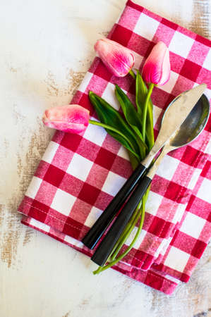 spring rusty table settings with fresh tulips, napkin and silverwareの写真素材