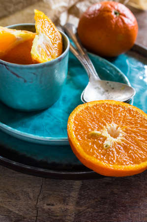 Sliced and whole orange fruit on bright turquoise ceramic plates over rusty wooden  backgroundの写真素材