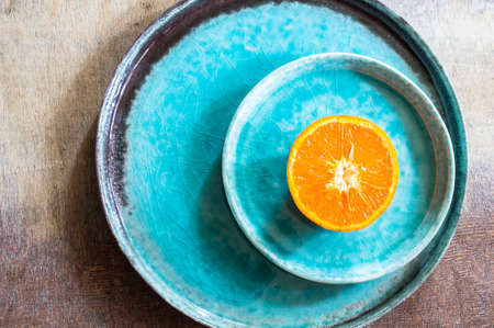 Sliced and whole orange fruit on bright turquoise ceramic plates over rusty wooden  backgroundの写真素材