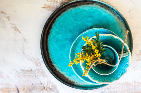 Spring time table decoration with yellow mimosa flowers and turquoise platesの写真素材