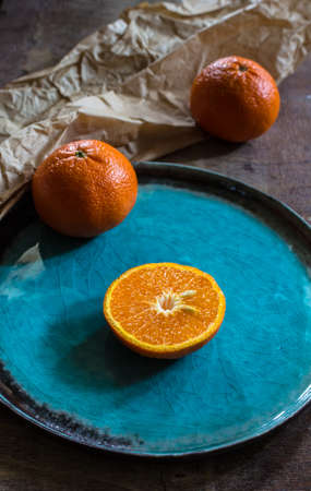 Sliced and whole orange fruit on bright turquoise ceramic plates over rusty wooden  backgroundの写真素材