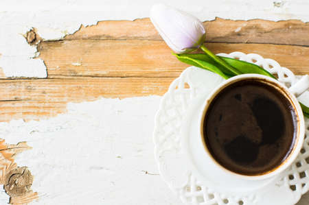 Cup of coffee with tulip flowers on rusty backgroundの写真素材