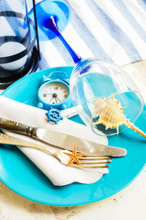 Marine table setting with vintage plate, silverware, napkin, wine glass and sea star in blue tones.の写真素材