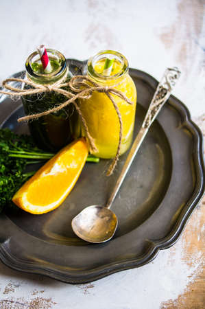 Vintage style bottles with fresh organic orange and green spinach smoothie on wooden table