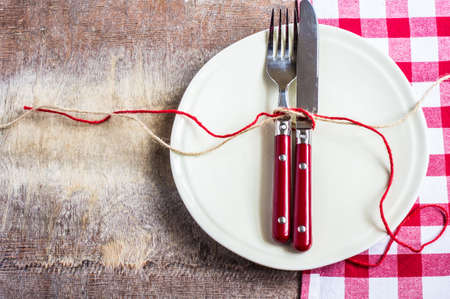 Rustic table setting with bright napkin, silverware and plate on old wooden table. View from above with copy spaceの写真素材