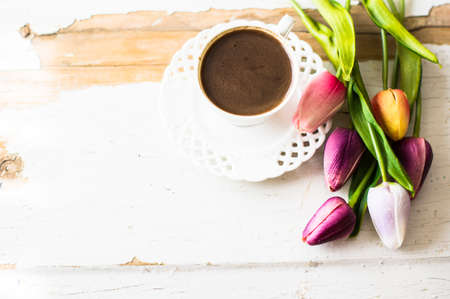 Cup of coffee with tulip flowers on rusty backgroundの写真素材