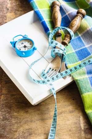 Silverware and measure tape on rustic background as a dieting conceptの写真素材