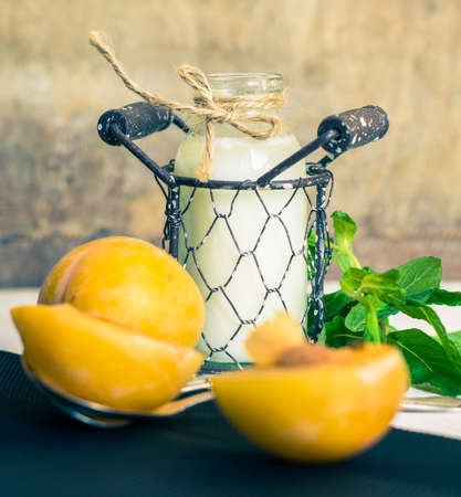 Glass of milk with mint and apricot fruits on rustic backgroundの写真素材