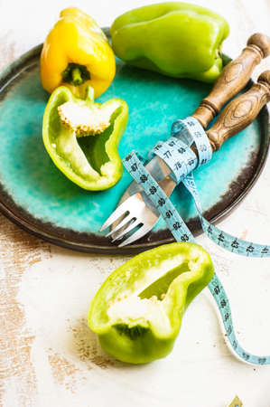 Diet concept with fresh bell pepper, silverware and measure tapeの写真素材