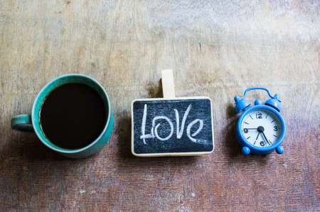 Cup of coffee and old-styled clock on rustic wooden tableの写真素材