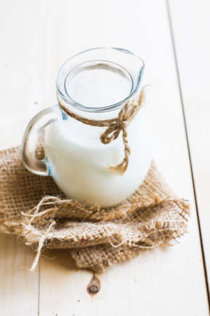 Old fashioned jar of milk on napkin on rustic wooden table.の写真素材