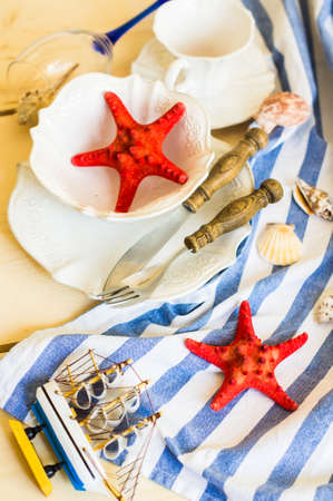 Rustic marine table setting with sea stars, vintage silverware and tableware on bright napkin