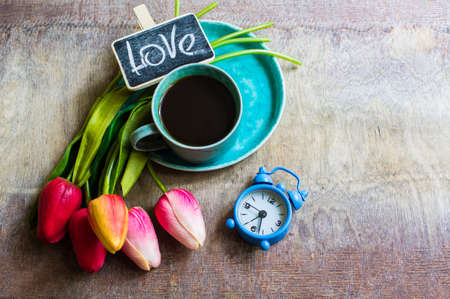 Cup of coffee and bright tulips with Love word on chalkboardの写真素材