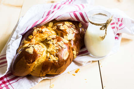 Freshly baked braided bread with almonds and milk  on rustic tableの写真素材