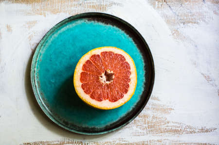 Fresh grapefruit on bright plate on vintage wooden backgroundの写真素材