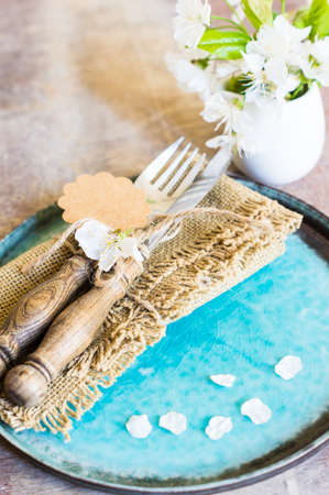 Spring time table setting with cherry blossom and vintage silverware on rustic background