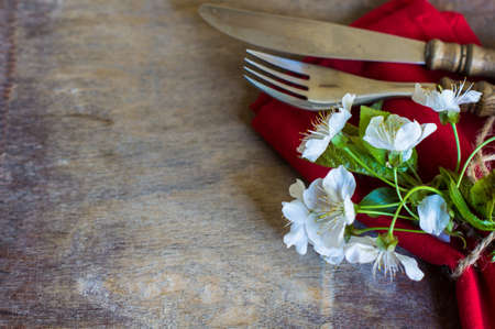 Spring time table setting with cherry blossom and vintage silverware on rustic background