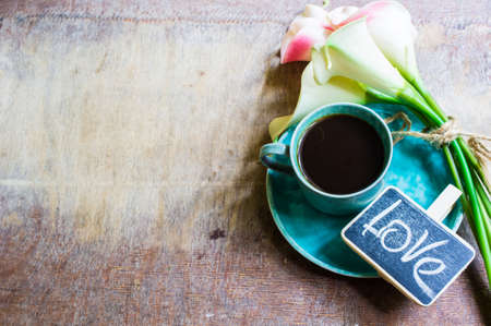 Cup of coffee and calla lily flowers on rusty background