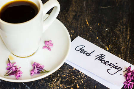 Lilac flowers and cup of coffee with good morning note on rustic wooden backgroundの写真素材