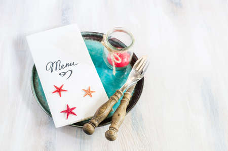 Rustic marine table setting with sea stars, vintage silverware and tableware on bright napkinの写真素材